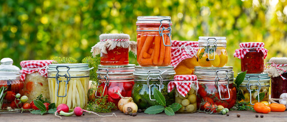 Homemade preserves,  pickles of various organic vegetables in jars on a wooden table