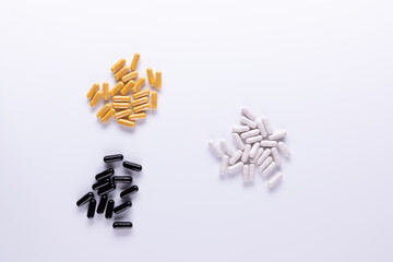 Fototapeta premium Yellow , black, white tablets and capsules lying on white background close-up.