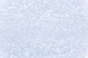 Close up macro photography texture of sparkling fresh white snow with light blue sky reflection tone. Selective focus. Winter christmas background.
