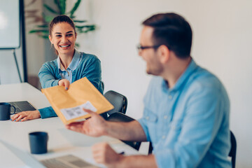 Businesswoman passing envelope to colleague in the office