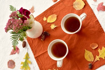 Warm fall beverage of hot tea with autumn leaves decor to sip and enjoy on cool seasonal days indoors