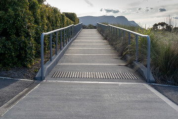 A concrete walkway with grey steel handrails leading to a carpark