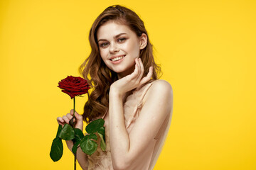 Romantic woman in evening dress with red rose on yellow background cropped view portrait
