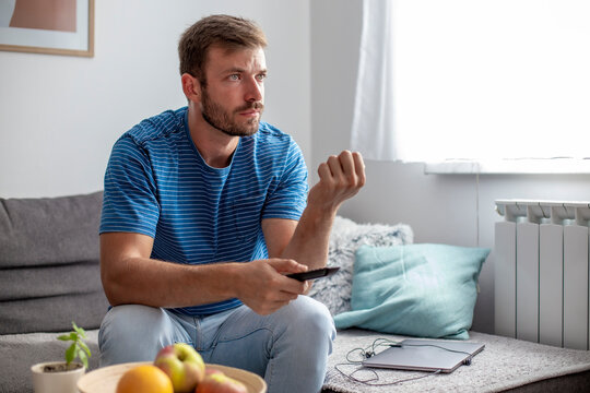 Young Man Watching Tv Seriously And Holding A Remote Control In His Hand