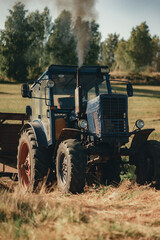 Farmer carries large round haystacks on his tractor.