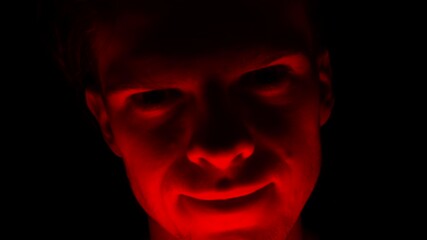 A scary and evil criminal man attacking a victim with a crazy smile and a look of violence and terror out of the dark night.