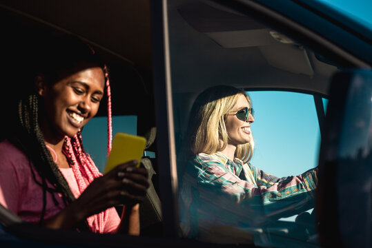 Happy Multiracial Friends Driving On Road Trip While Using Gps Mobile Phone App - Lifestyle Camper Tech Concept - Focus On Girl On Right