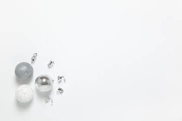 Festive composition. Three silver Christmas balls and tinsel on white background, copy space. Concept preparing gifts, packaging, tree decoration. Horizontal, flat lay. Top view