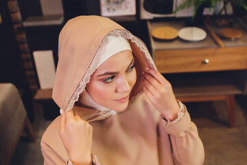 Portrait of positive pretty young Arabian woman in pink headscarf touching face with hand.