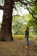 Attractive young female wearing a black leather jacket while walking and witnessing the surrounding nature at Richmond Park