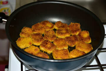 Cooking ruddy chicken nuggets in sunflower oil in a frying pan