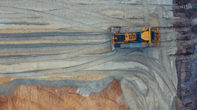 Aerial top down view of a bulldozer is leveling ground on the developable site. Roadworks