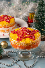 Festive New Year's salad with chicken, eggs, carrots and corn, decorated with a star of pomegranate seeds on light blue background