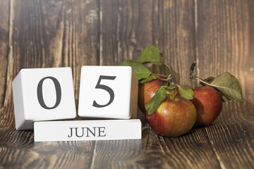 June 5. Day 05 of month. Calendar cube on wooden background with red apples, concept of business and an important event. Summer season.