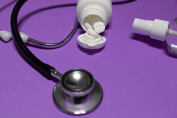 Tabletki wysypujące się z pojemnika, Stetoskop dezynfekcja - fioletowe tło 