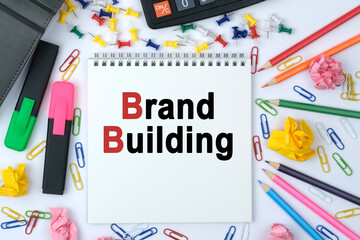 On the table is a calculator, diary, markers, pencils and a notebook with the inscription - Brand Building