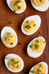 Homemade Deviled Eggs with Chives on a rustic wooden board, overhead view. Flat lay, top view, from above.
