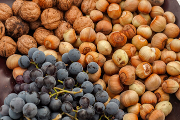 Ripe raw hazelnuts, walnuts and red grape closeup as food background