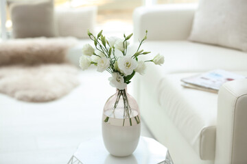 Vase with fresh flowers on white table in living room