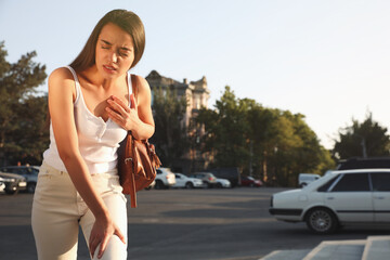 Young woman having heart attack on city street