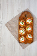 Homemade Blini with Smoked Salmon, Creme and Chives on a rustic wooden board, top view. Flat lay, overhead, from above. Copy space.