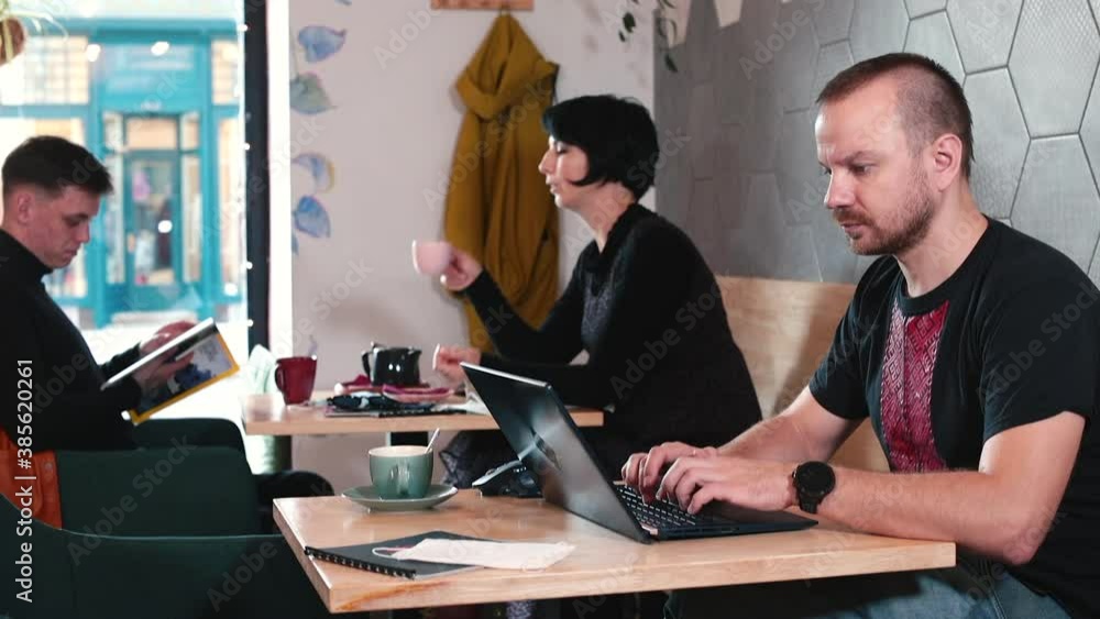 Poster guests in a cozy cafe are busy with their own business. the couple came on a date. male freelancer w