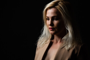Fototapeta premium Young beautiful blond glamorous woman in black over dark background