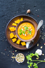 Delicious healthy pumpkin soup, herbs, and ingredients for the dish. Creative atmospheric decoration