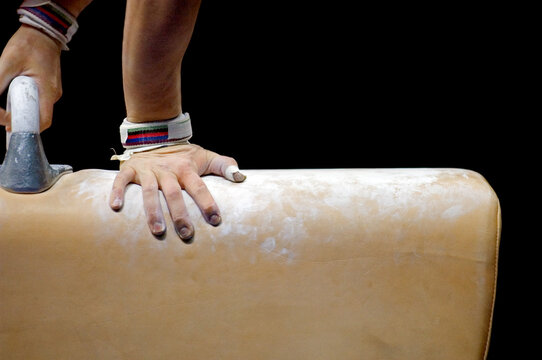 Closeup Of A Gymnast's Hands With Chalk And Protective Equipment In A Gymnastics Competition.