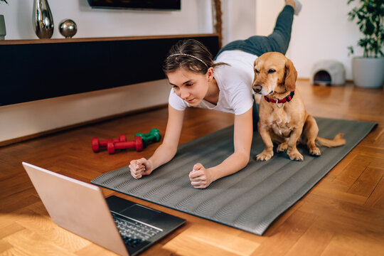 girl watching exercise tutorials online with her dog