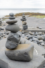 Stacked rocks into a standing still formation, pebbles by the beach put one on another as hihg as possible, groups of stones in vertical positions standing on each other