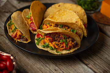 Tasty mexican tacos with meat on black round plate on rustic wooden table. Traditional mexican...