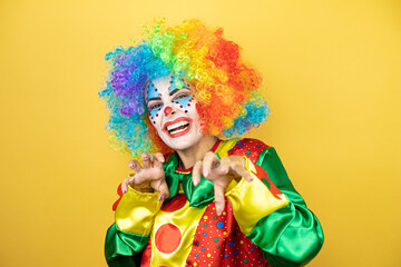 Clown standing over yellow insolated yellow background smiling funny doing claw gesture as cat, aggressive and sexy expression