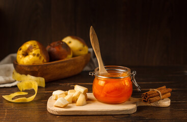 Apple jam in a small glass jar on a wooden Board with Apple slices and cinnamon sticks. a bowl of...