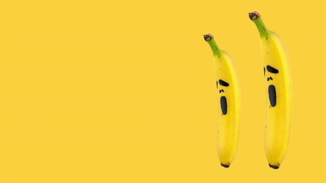 seamless looping animation of two bananas with painted on them scary mask of fear on a yellow background. Halloween concept for copy space
