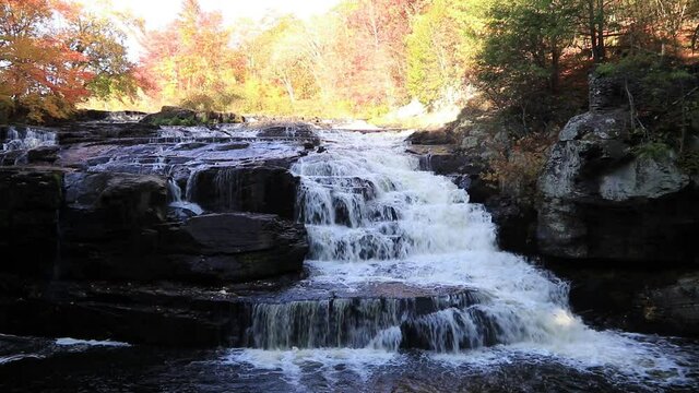 Peak fall foliage surrounds beautiful cascading lower Shohola Falls on an Autumn morning in the Pennsylvania Poconos