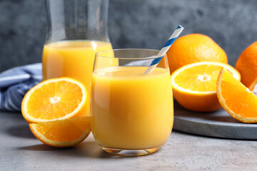 Glass of orange juice and fresh fruits on grey table, closeup