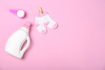 Flat lay composition with bottle of detergent and children's socks on pink background. Space for text
