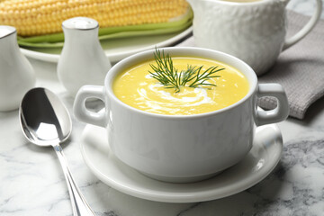 Delicious creamy corn soup served on white marble table
