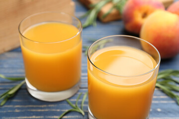 Glasses of natural peach juice on blue wooden table, closeup
