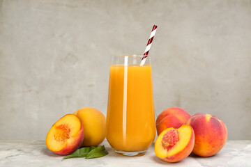 Natural peach juice and fresh fruits on grey table