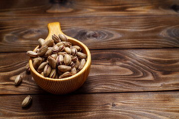 Pistachios in a wooden Cup on a wooden background. Space for text