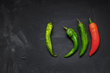 Hot peppers spoiled on a dark background. Ugly food. Space for text