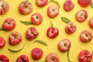 Fresh donut peaches with leaves on yellow background, flat lay