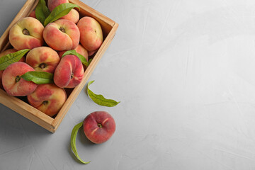 Fresh ripe donut peaches with leaves on light table, flat lay. Space for text