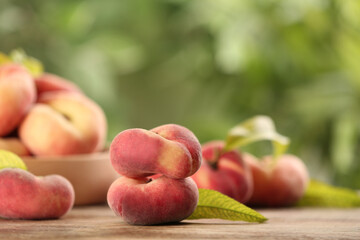 Fototapeta na wymiar Fresh ripe donut peaches on wooden table against blurred green background. Space for text