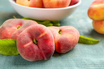 Fresh ripe donut peaches on light blue wooden table, closeup