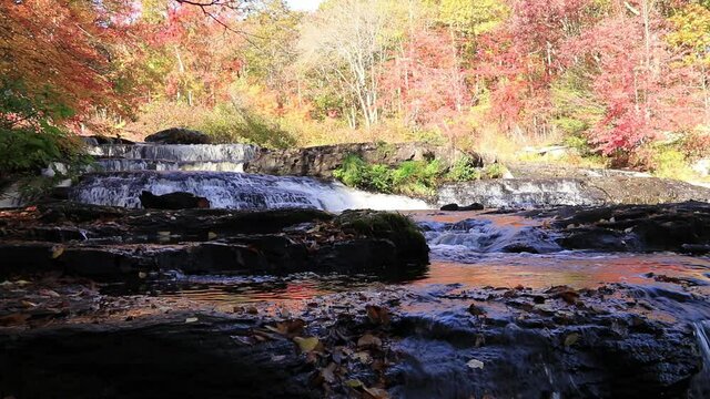 Peak fall foliage surrounds beautiful cascading upper side Shohola Falls on an Autumn morning in the Pennsylvania Poconos