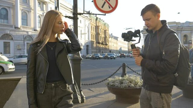 A male videographer shoots two female models walking around the city. A videograph at work. Shooting girls in the city.