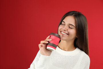 Happy beautiful woman with paper cup of mulled wine on red background. Space for text